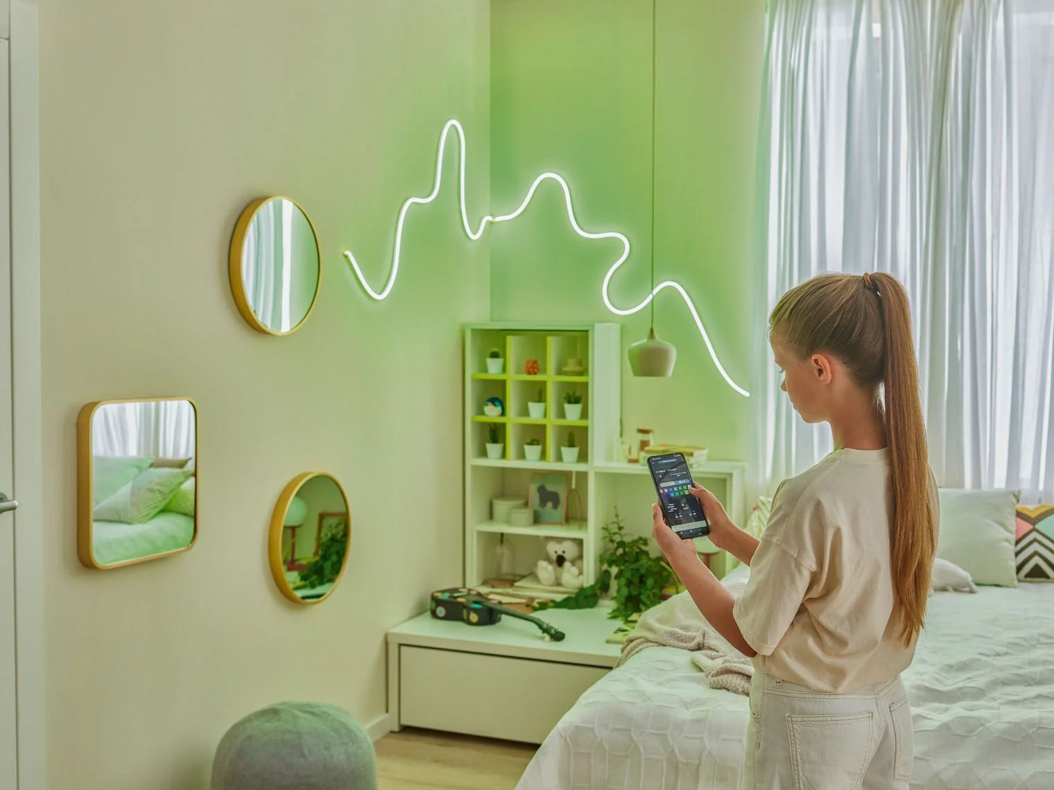  Dziewczynka sterująca nowoczesnym, neonowym oświetleniem ściennym za pomocą smartfona 